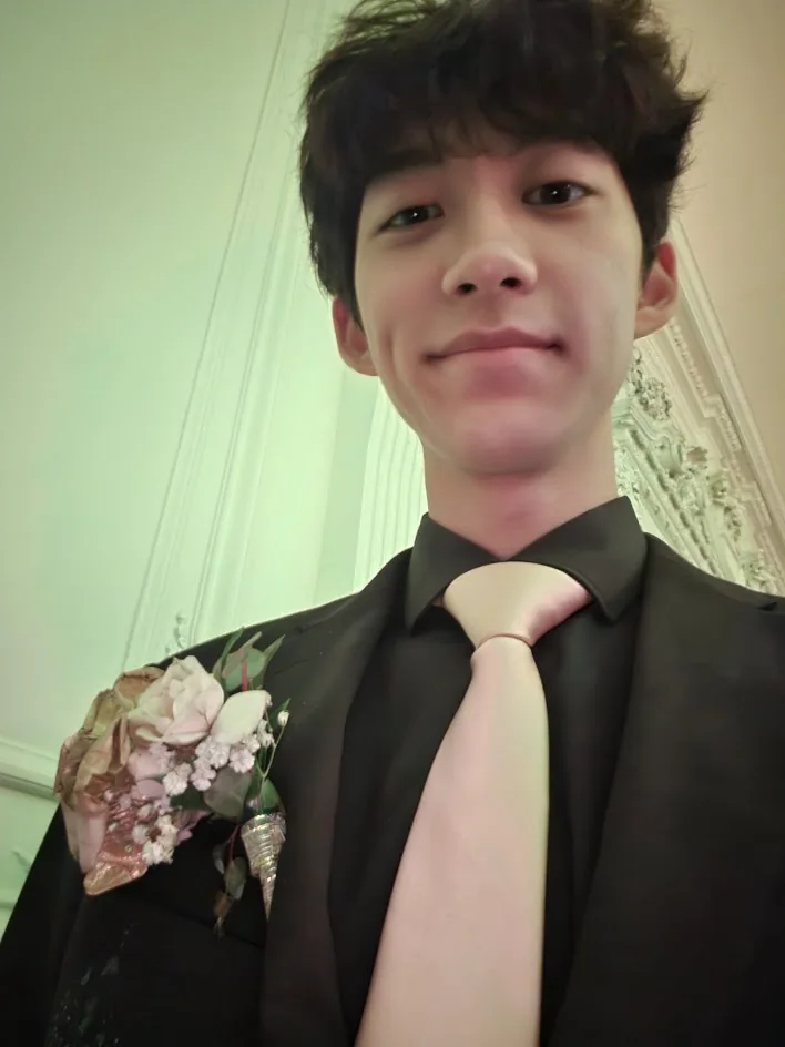 Aaron in a black suit with a pink tie and a boutonniere