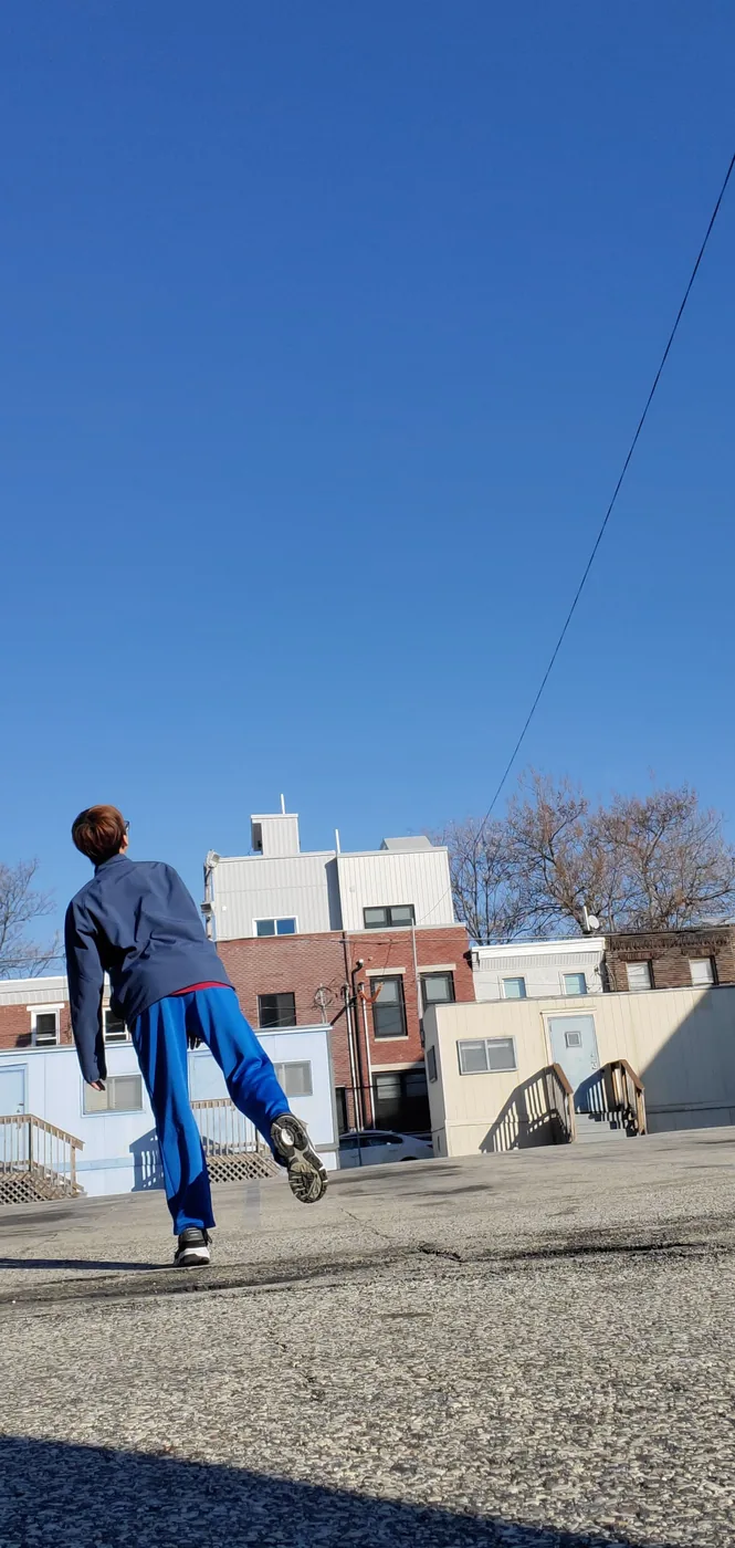 Aaron mid-jump outdoors under a blue sky