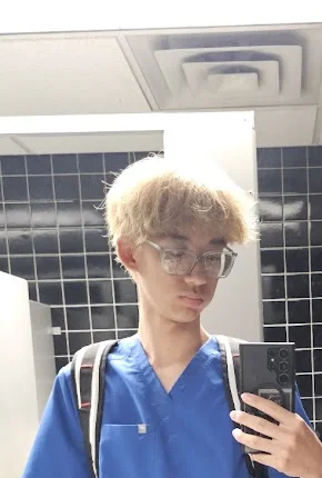 Aaron in blue scrubs with a backpack
